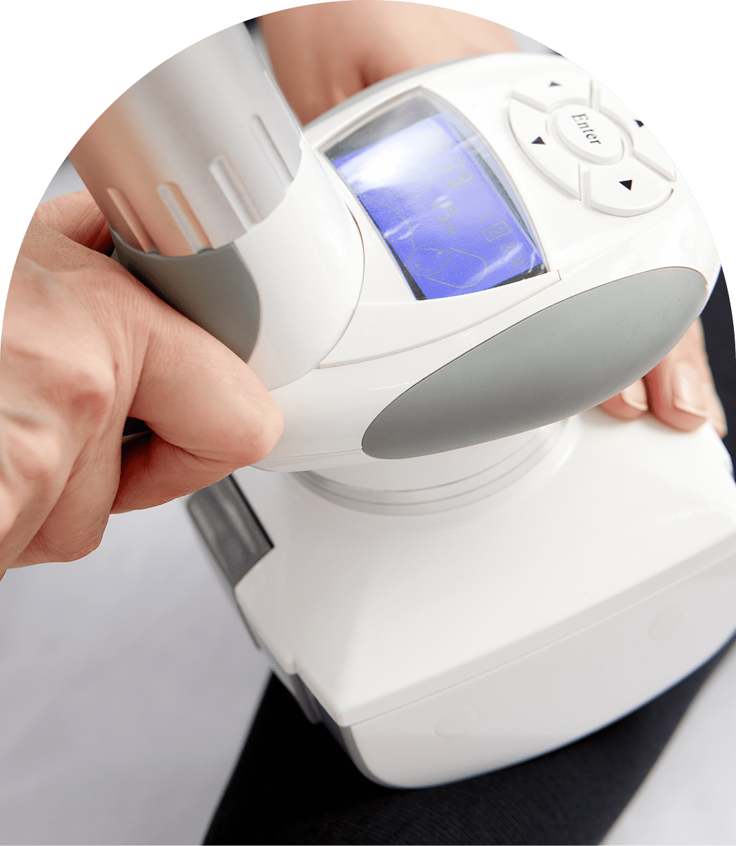 A person holding and operating a white and gray device with a digital screen and buttons, possibly a handheld electronic gadget, against a black background.