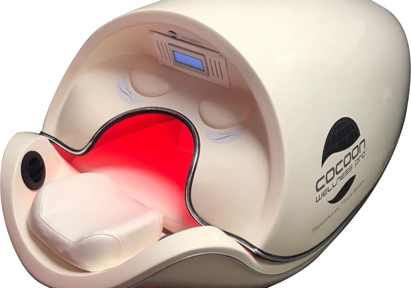 A futuristic, pod-shaped wellness device with an open door, featuring a red-lit interior and the text "Cocoon Wellness Pro" on its side.